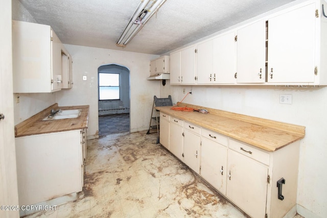 kitchen featuring sink, a textured ceiling, white cabinets, and baseboard heating