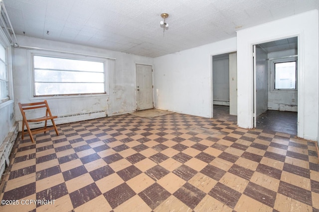 unfurnished room with a baseboard radiator and a healthy amount of sunlight