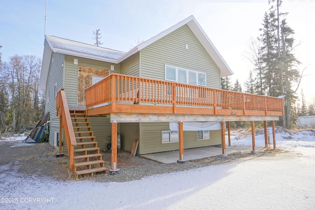 snow covered back of property with a deck