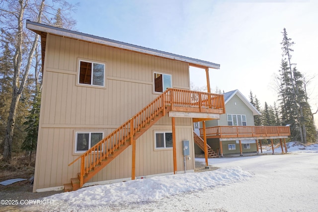 snow covered house featuring a wooden deck