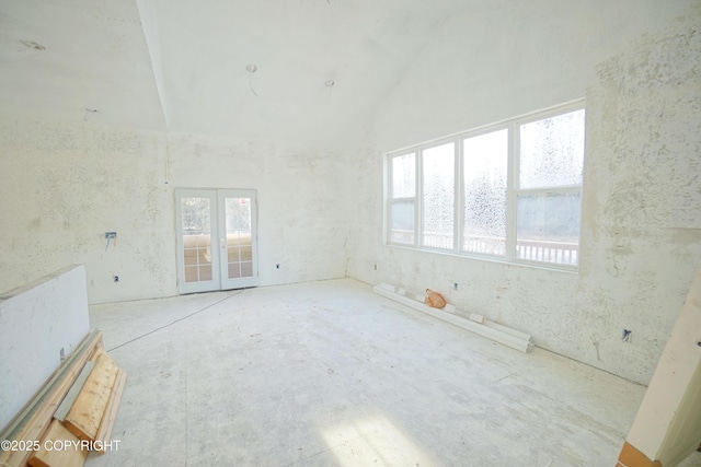 spare room with high vaulted ceiling, french doors, and a healthy amount of sunlight