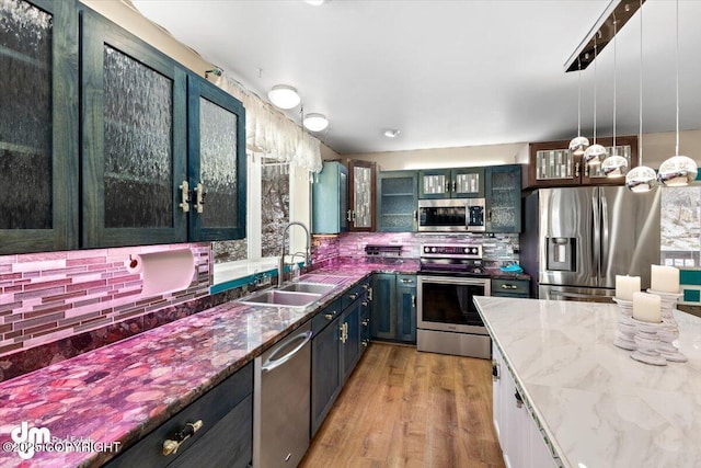 kitchen with sink, appliances with stainless steel finishes, white cabinetry, backsplash, and dark stone counters