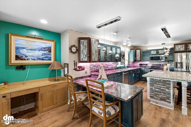 kitchen featuring hanging light fixtures, stainless steel appliances, a center island, and dark stone counters