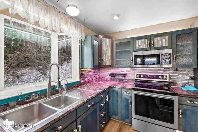 kitchen featuring appliances with stainless steel finishes, sink, backsplash, and light hardwood / wood-style flooring