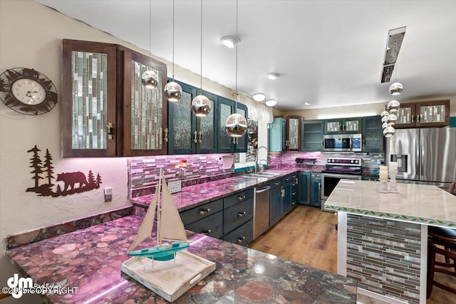 kitchen featuring a kitchen island, pendant lighting, sink, dark stone countertops, and stainless steel appliances