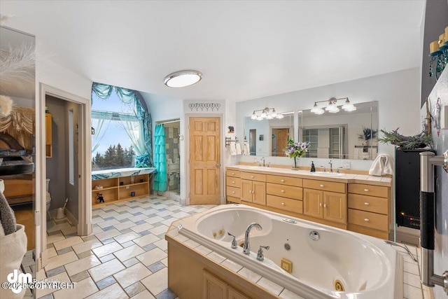 bathroom with vanity, tiled bath, and toilet