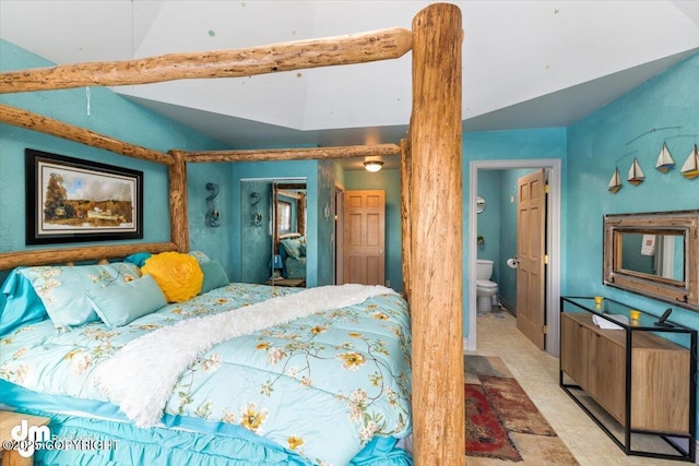 bedroom with ensuite bathroom and vaulted ceiling with beams