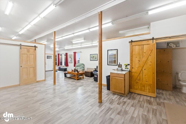 basement with a barn door and light hardwood / wood-style floors