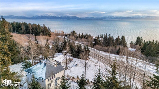 snowy aerial view featuring a water and mountain view