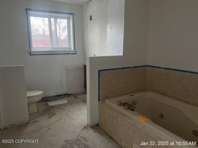 bathroom featuring tiled bath and toilet