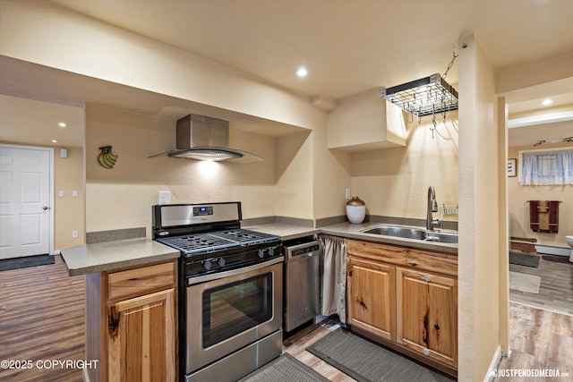 kitchen featuring appliances with stainless steel finishes, sink, wall chimney range hood, and light hardwood / wood-style flooring