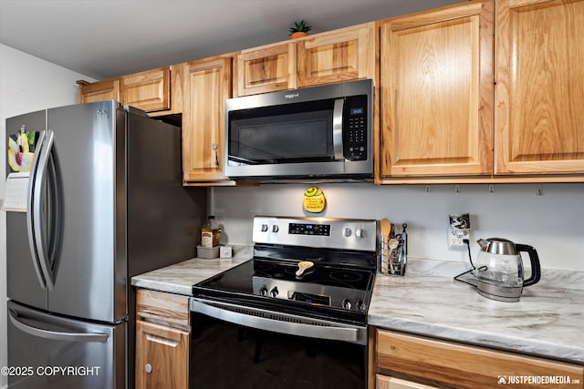 kitchen featuring stainless steel appliances and light stone countertops