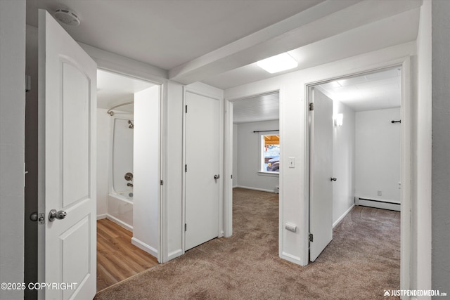 hall with light colored carpet and baseboard heating