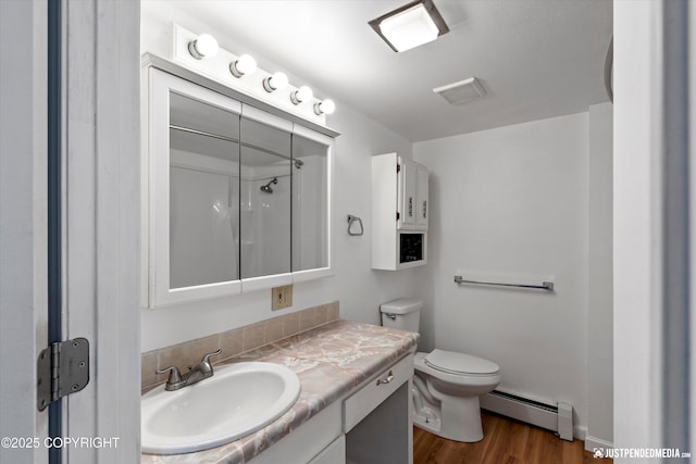 bathroom with hardwood / wood-style flooring, a baseboard heating unit, vanity, a shower, and toilet