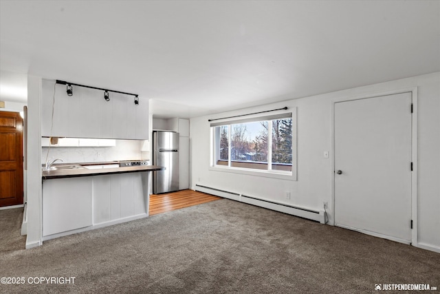 unfurnished living room featuring baseboard heating, light colored carpet, and sink