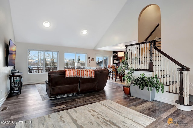 living room featuring dark wood-type flooring, a wealth of natural light, and high vaulted ceiling