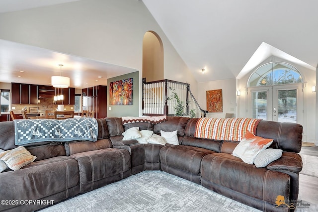 living room with light hardwood / wood-style flooring, high vaulted ceiling, and french doors