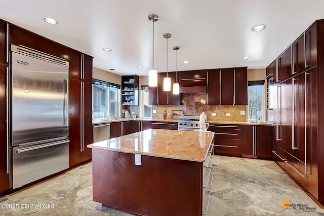 kitchen with light stone counters, a center island, premium appliances, pendant lighting, and decorative backsplash