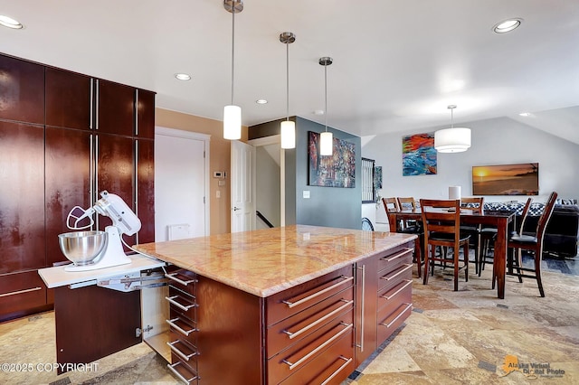 kitchen featuring light stone counters, decorative light fixtures, vaulted ceiling, and a kitchen island