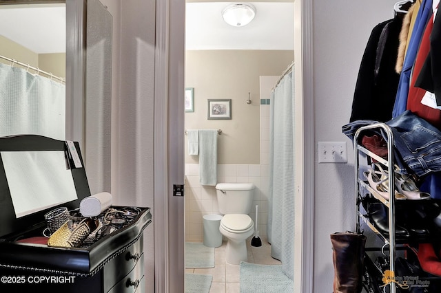 bathroom with tile patterned floors, toilet, and tile walls