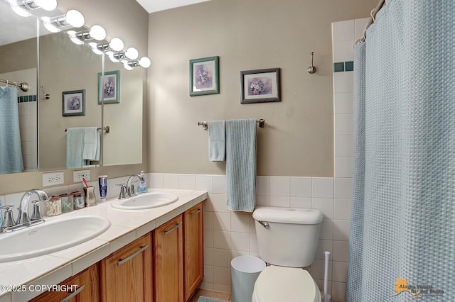 bathroom with walk in shower, vanity, toilet, and tile walls