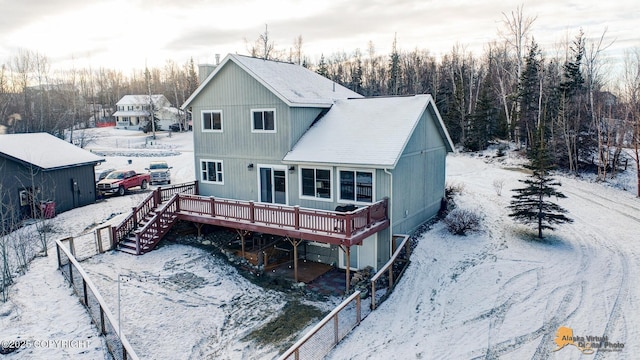 snow covered house featuring a wooden deck