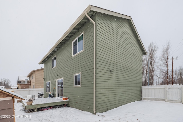 snow covered rear of property with a deck