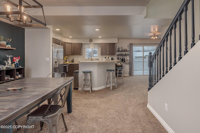 dining room featuring sink, light carpet, and an inviting chandelier