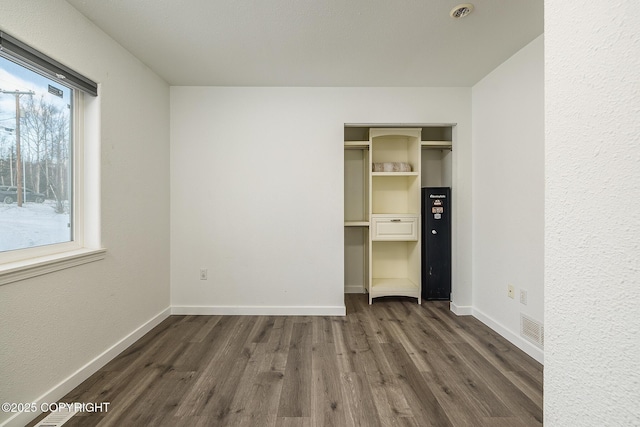 unfurnished bedroom with dark hardwood / wood-style floors and a closet