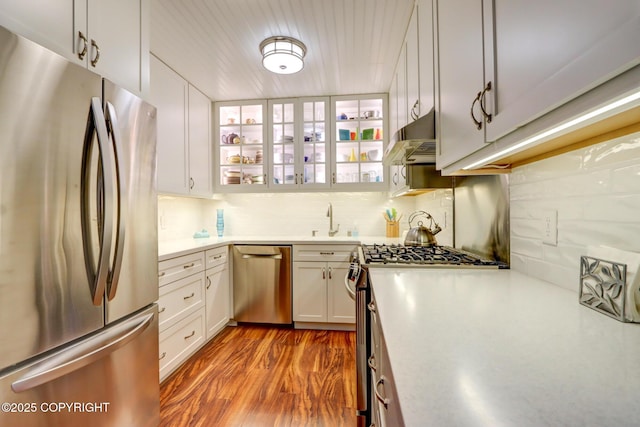 kitchen featuring sink, white cabinetry, stainless steel appliances, light hardwood / wood-style floors, and backsplash