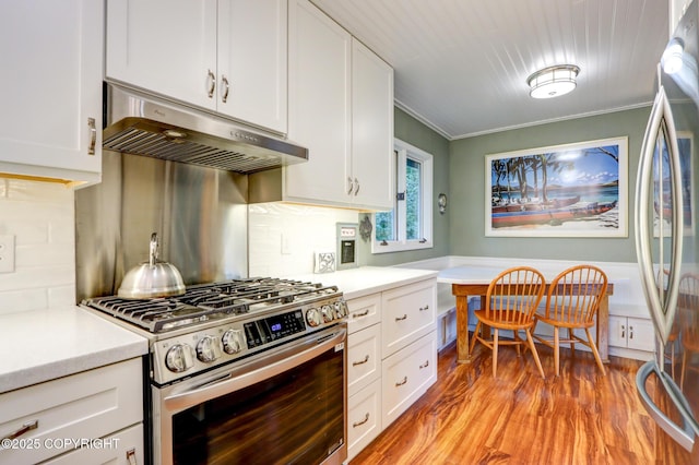 kitchen with ornamental molding, stainless steel appliances, light hardwood / wood-style floors, decorative backsplash, and white cabinets