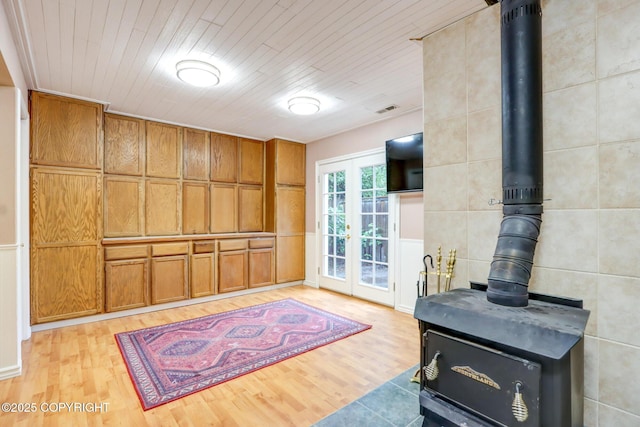 kitchen with a wood stove, light hardwood / wood-style floors, and french doors