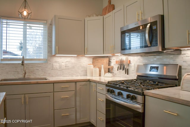 kitchen featuring sink, tasteful backsplash, gray cabinets, stainless steel appliances, and light stone countertops