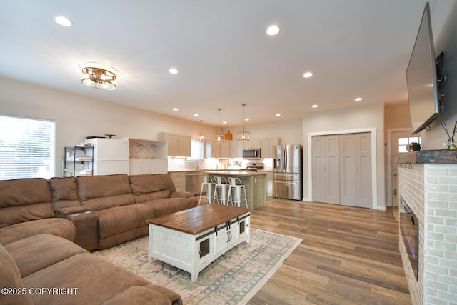 living room with a brick fireplace and light hardwood / wood-style floors