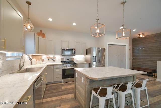 kitchen featuring a kitchen island, appliances with stainless steel finishes, tasteful backsplash, sink, and a breakfast bar area