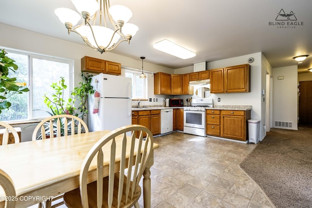 6976 W Windsor Dr, Wasilla, AK 99623 - kitchen with white appliances, brown cabinets, a chandelier, light countertops, and decorative light fixtures