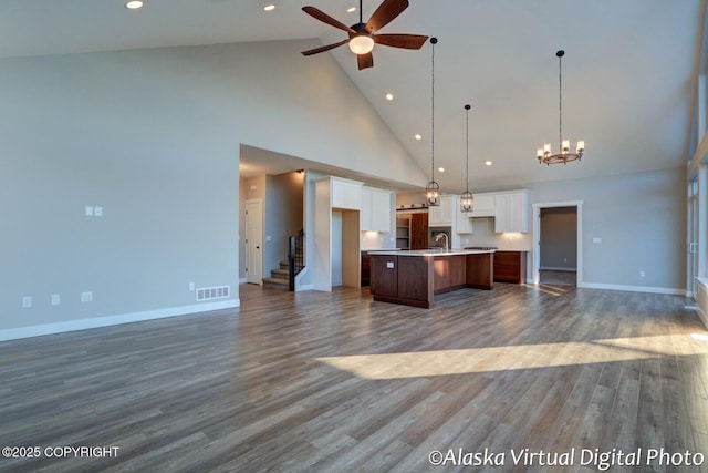 kitchen featuring hanging light fixtures, white cabinetry, a kitchen island with sink, and dark hardwood / wood-style floors