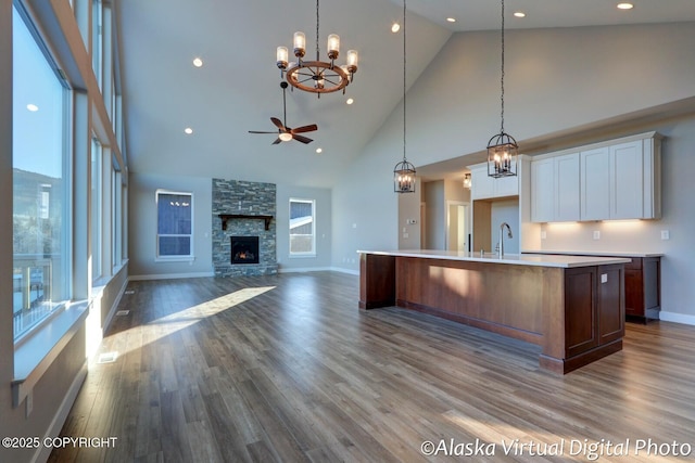 kitchen featuring a fireplace, white cabinetry, sink, hanging light fixtures, and a kitchen island with sink