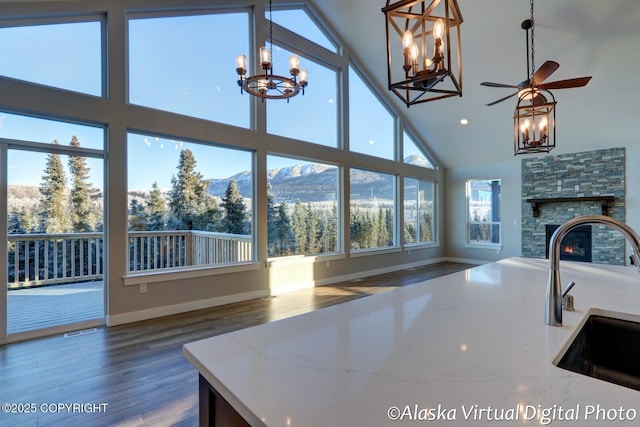 kitchen featuring high vaulted ceiling, a fireplace, sink, light stone counters, and a mountain view