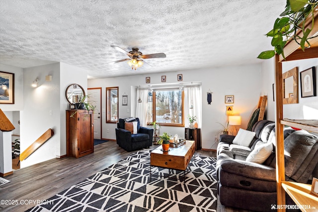 living room featuring ceiling fan, dark wood-type flooring, and a textured ceiling