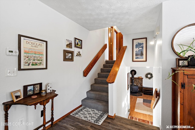 staircase with hardwood / wood-style floors and a textured ceiling