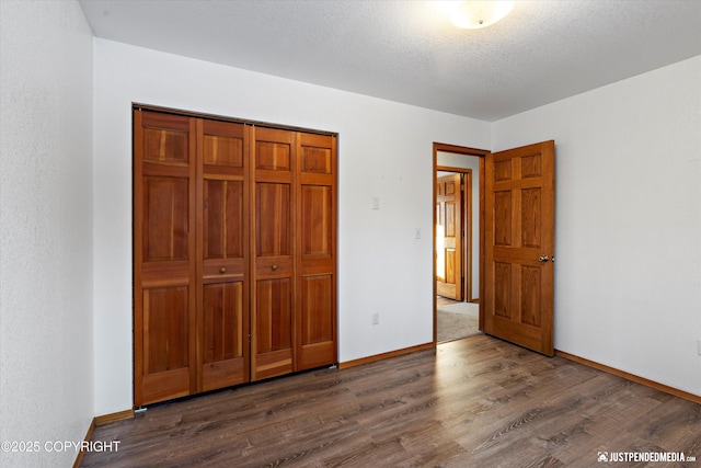 unfurnished bedroom with a closet, dark hardwood / wood-style floors, and a textured ceiling