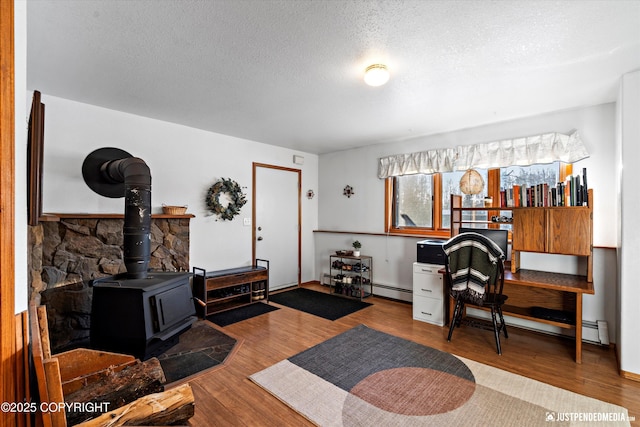 office with wood-type flooring, a wood stove, a textured ceiling, and baseboard heating