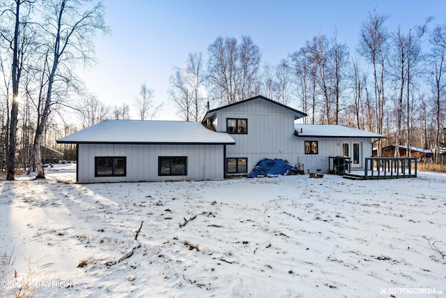 snow covered back of property featuring a wooden deck