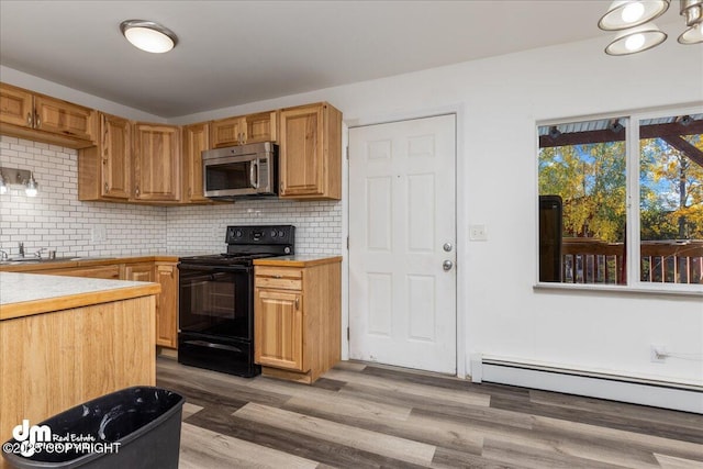 kitchen featuring black / electric stove, light countertops, baseboard heating, backsplash, and stainless steel microwave