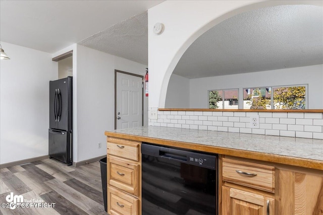 kitchen with dark wood finished floors, freestanding refrigerator, light countertops, a textured ceiling, and backsplash