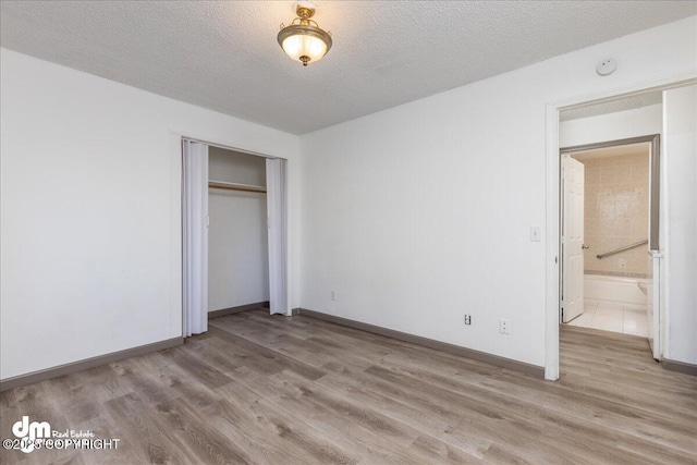 unfurnished bedroom with light wood-type flooring, a closet, and a textured ceiling