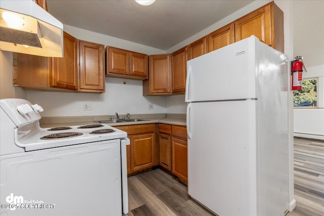 kitchen featuring white appliances, brown cabinets, light countertops, under cabinet range hood, and a sink