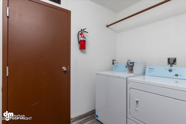 washroom with laundry area, washer and clothes dryer, and wood finished floors