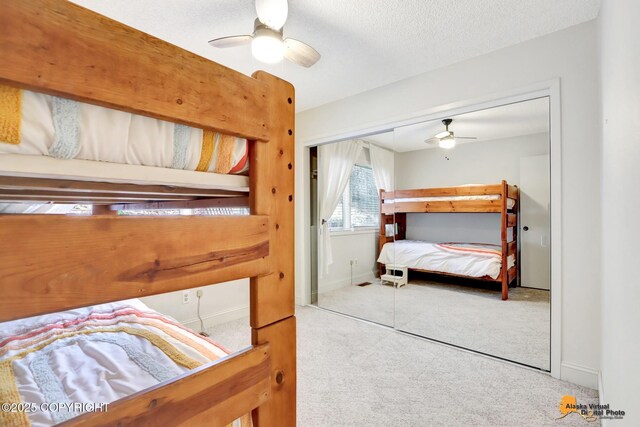 bedroom with a closet, light carpet, ceiling fan, and a textured ceiling